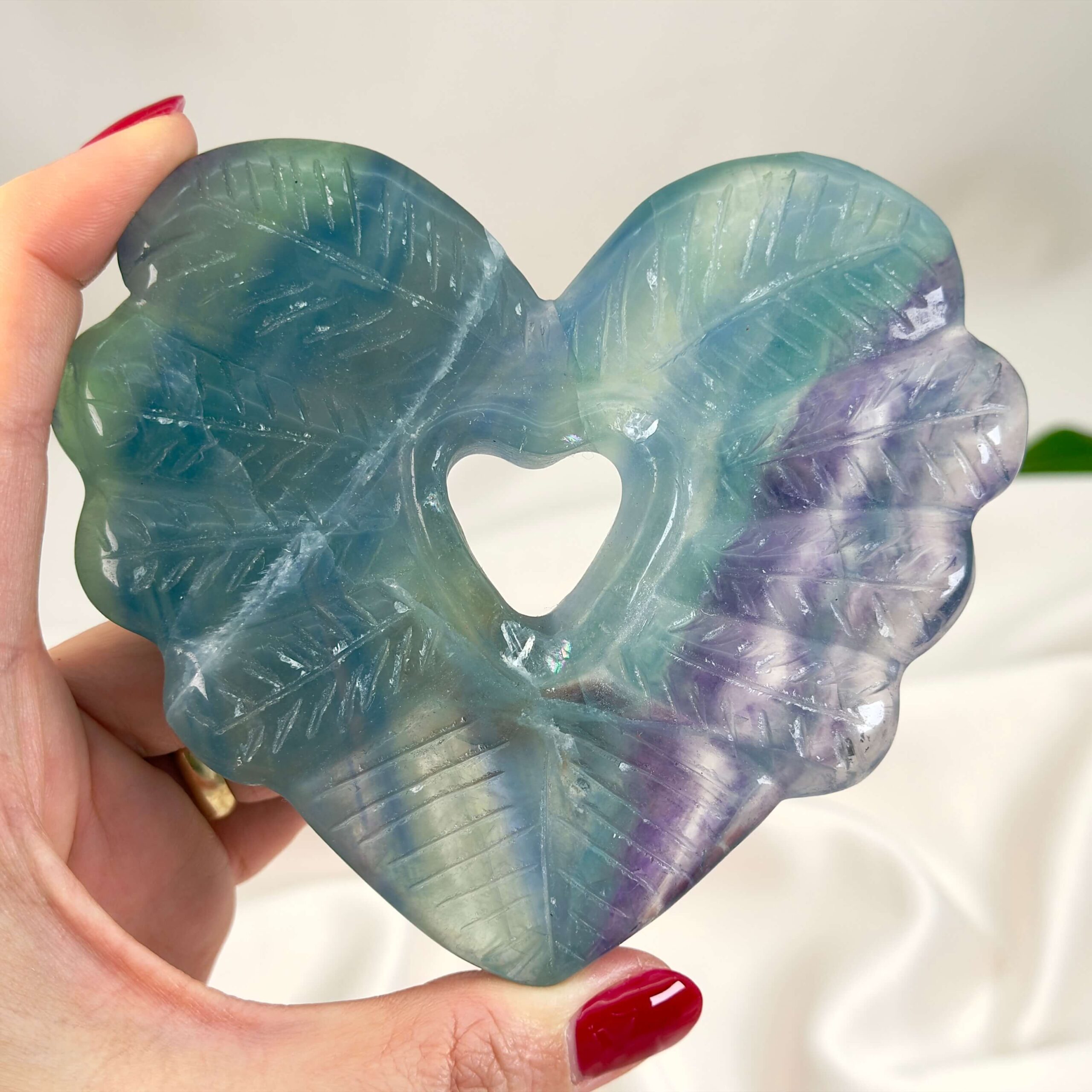 Fluorit Regnbue Hjerte krystal sten i hånd på hvid baggrund