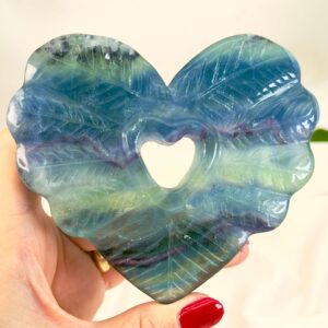 Fluorit Regnbue Hjerte krystal sten i hånd på hvid baggrund