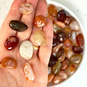 Karneol Lommesten Krystal i hånd på hvid baggrund