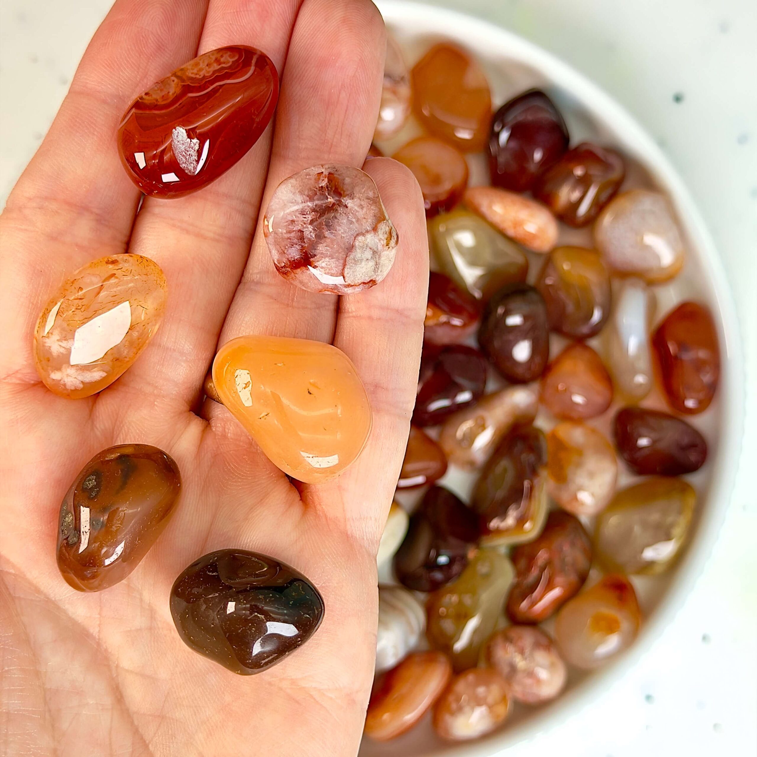 Karneol Lommesten Krystal i hånd på hvid baggrund