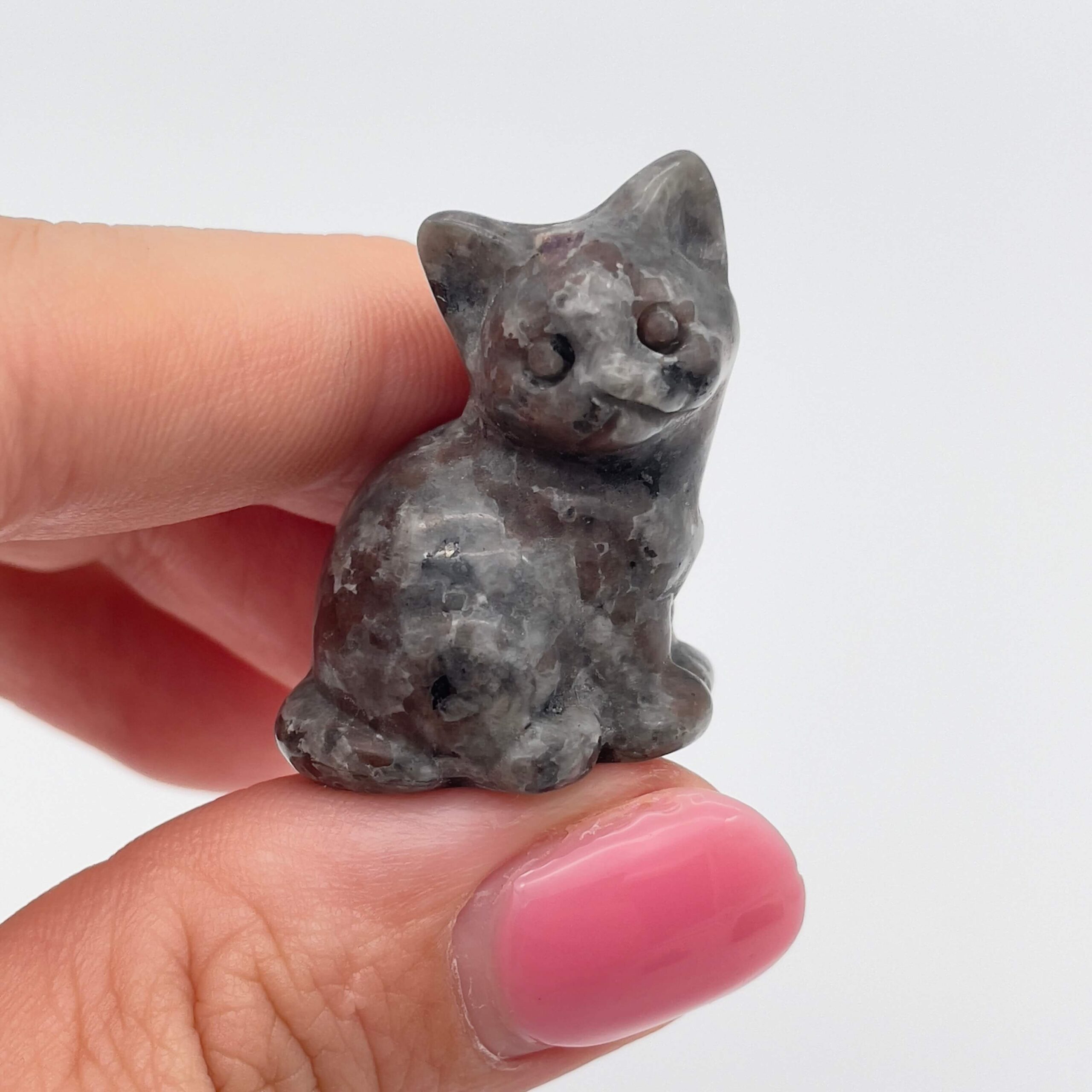 Sten krystal kat 3 cm yooperlite mellem fingre på hvid baggrund