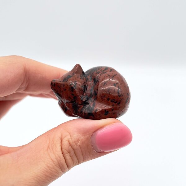 Sten krystal kat 4 cm obsidian mahogni mellem fingre på hvid baggrund