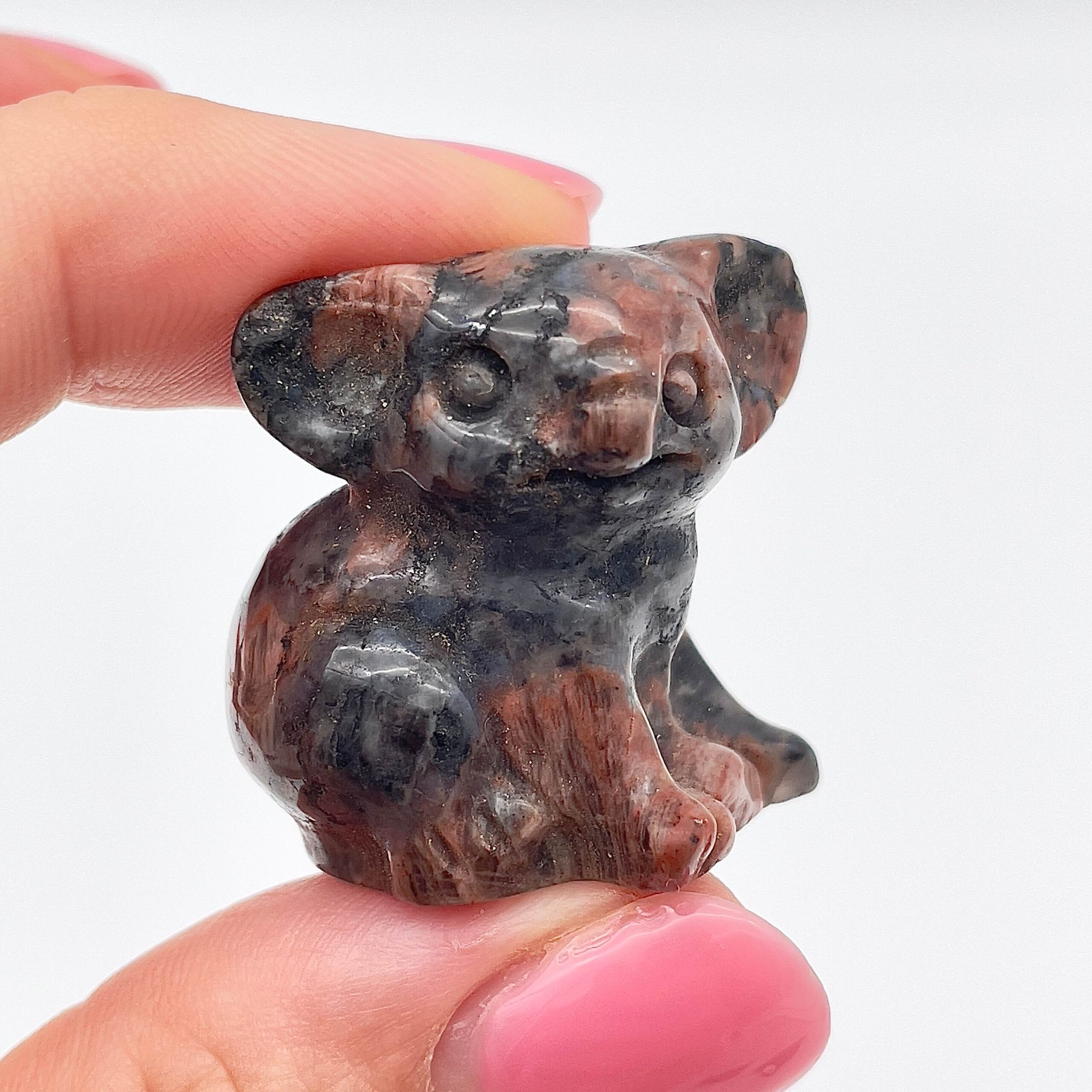 Sten krystal koala 3 cm yooperlite imellem fingre på hvid baggrund