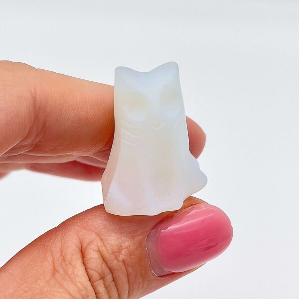 Sten krystal spøgelseskat 3 cm opalit mellem fingre på hvid baggrund