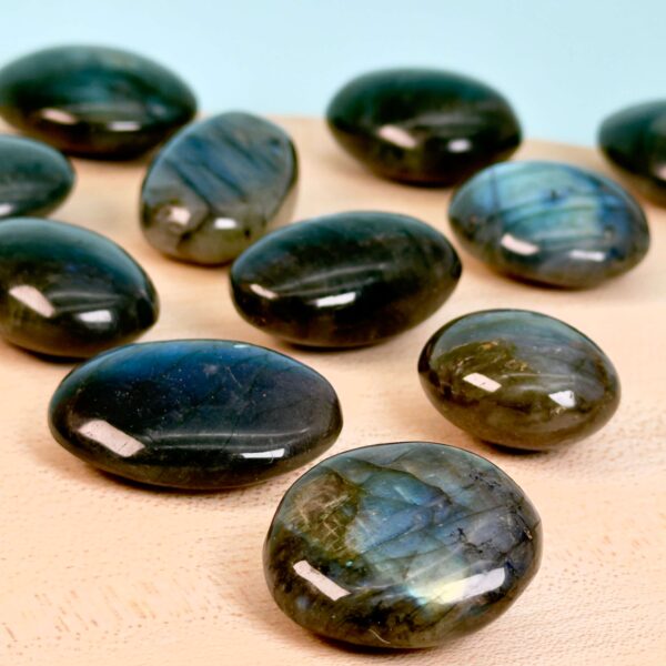 Labradorit Premium Lommesten Krystal Sten på træ og blå baggrund