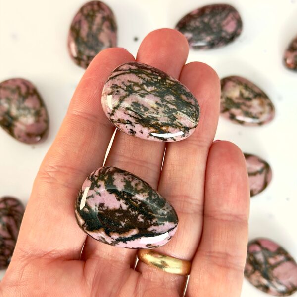 Rhodonit dråbe premium lommesten krystal sten i hånd på hvid baggrund