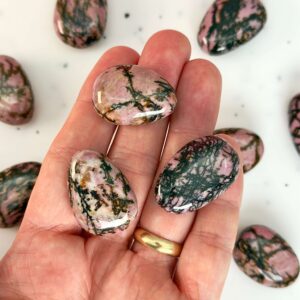 Rhodonit dråbe premium lommesten krystal sten i hånd på hvid baggrund