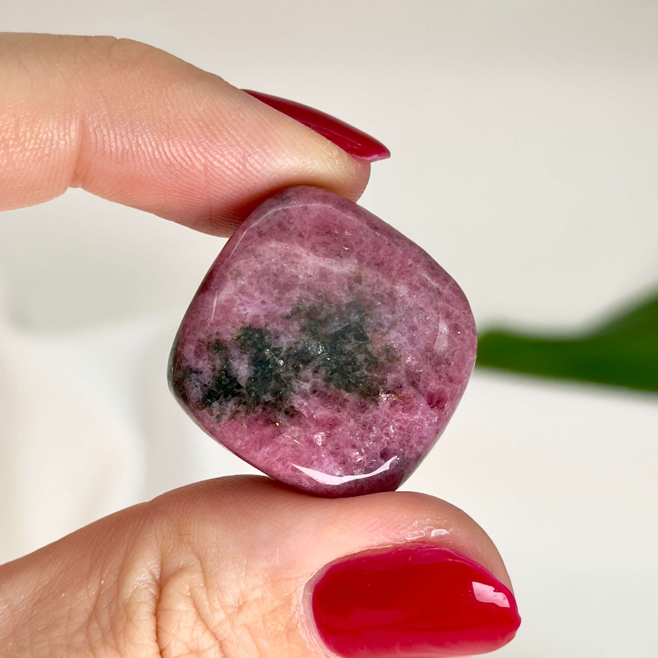 Rhodonit Lommesten sten krystal sten i hånd på hvid baggrund
