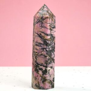 Rhodonit Tårn krystal sten på hvid og rosa baggrund