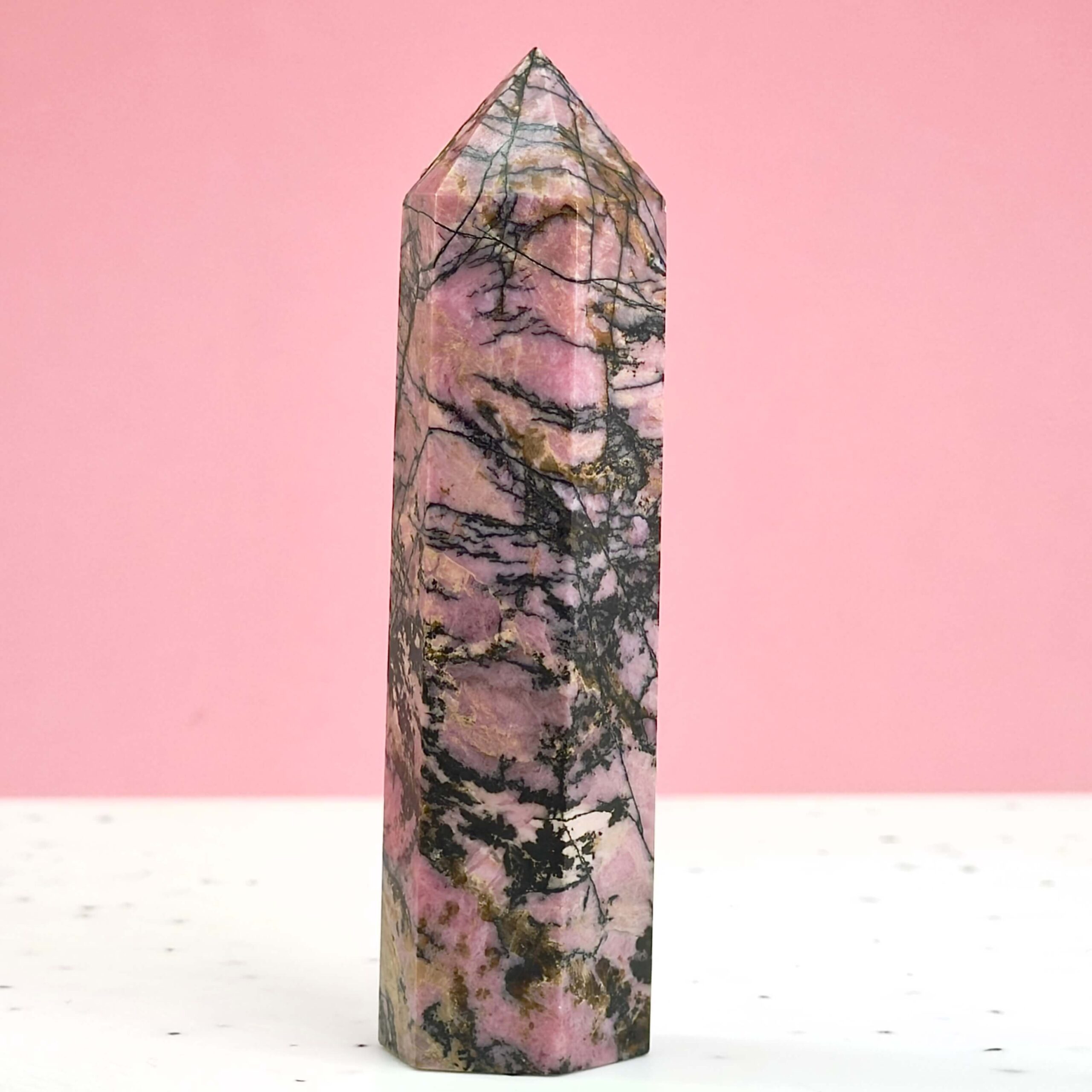 Rhodonit Tårn krystal sten på hvid og rosa baggrund