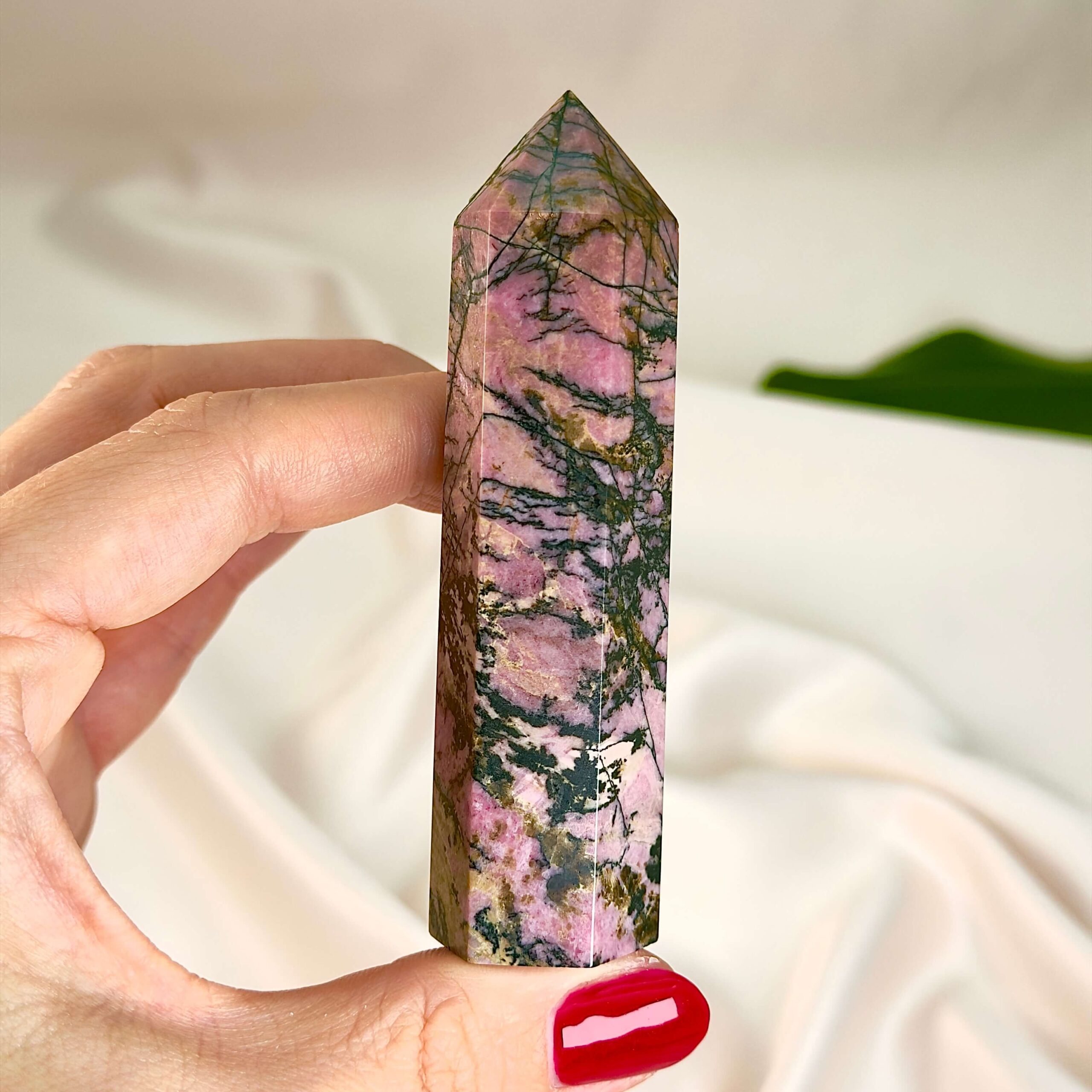 Rhodonit Tårn krystal sten i hånd på hvid baggrund