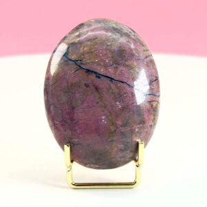 Rhodonit håndsten krystal sten i holder på hvid plade med lyserød baggrund