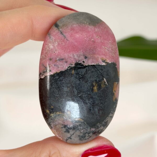 Rhodonit håndsten krystal sten i hånd med hvid baggrund