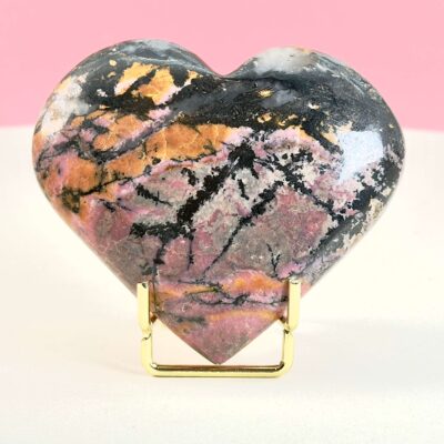 Rhodonit hjerte krystal sten i holder på hvid plade med lyserød baggrund