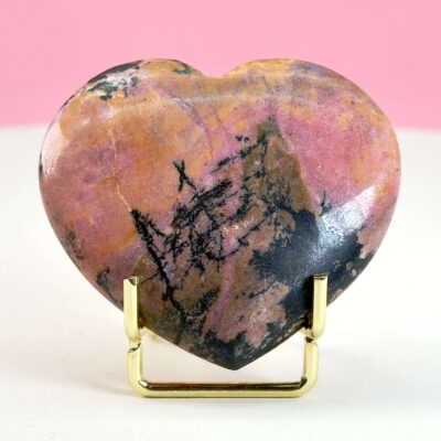 Rhodonit hjerte krystal sten i holder på hvid plade med lyserød baggrund