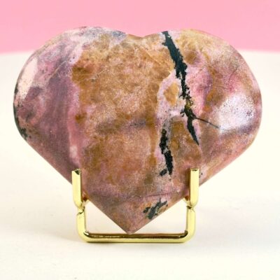 Rhodonit hjerte krystal sten i holder på hvid plade med lyserød baggrund