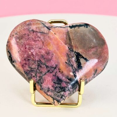 Rhodonit hjerte krystal sten i holder på hvid plade med lyserød baggrund