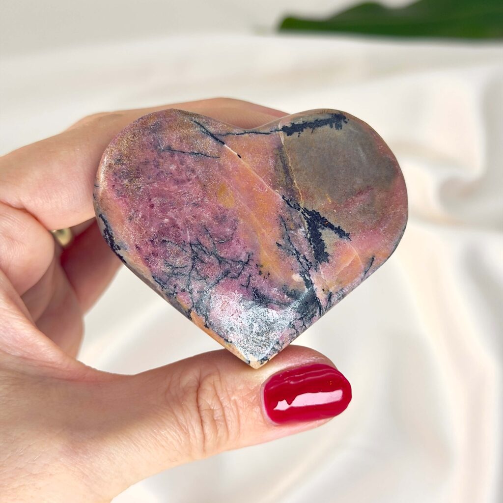 Rosakvarts vs. Rhodonit 2 Rhodonit hjerte krystal sten i hånd med hvid baggrund