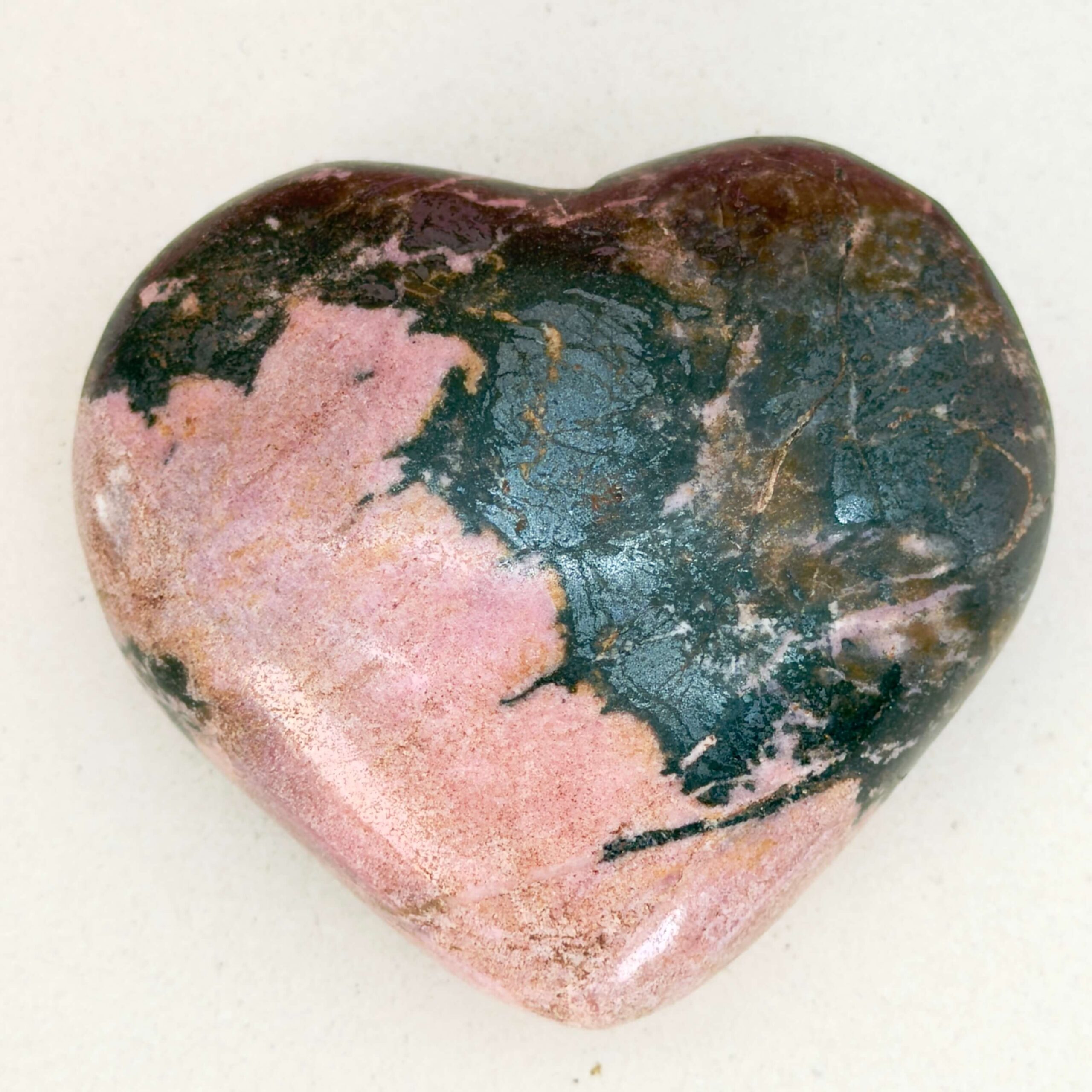 Rhodonit hjerte krystal sten i holder på hvid plade