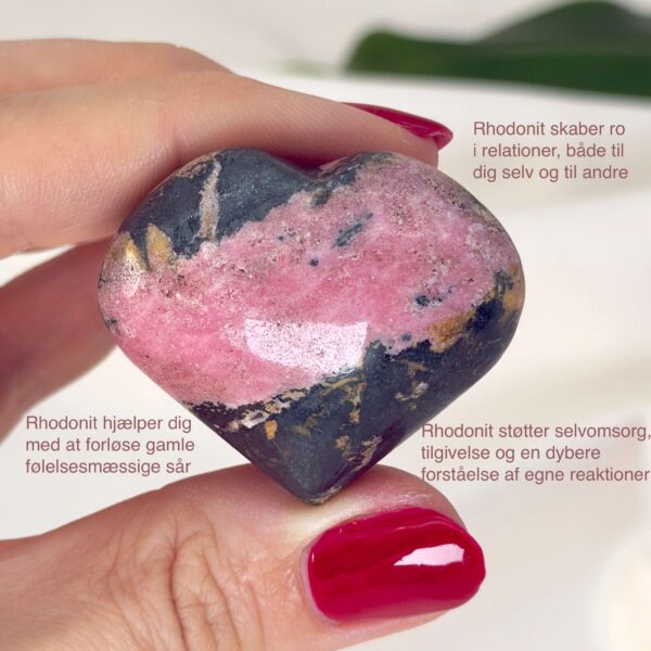 Rhodonit hjerte krystal sten i hånd med hvid baggrund og med tags