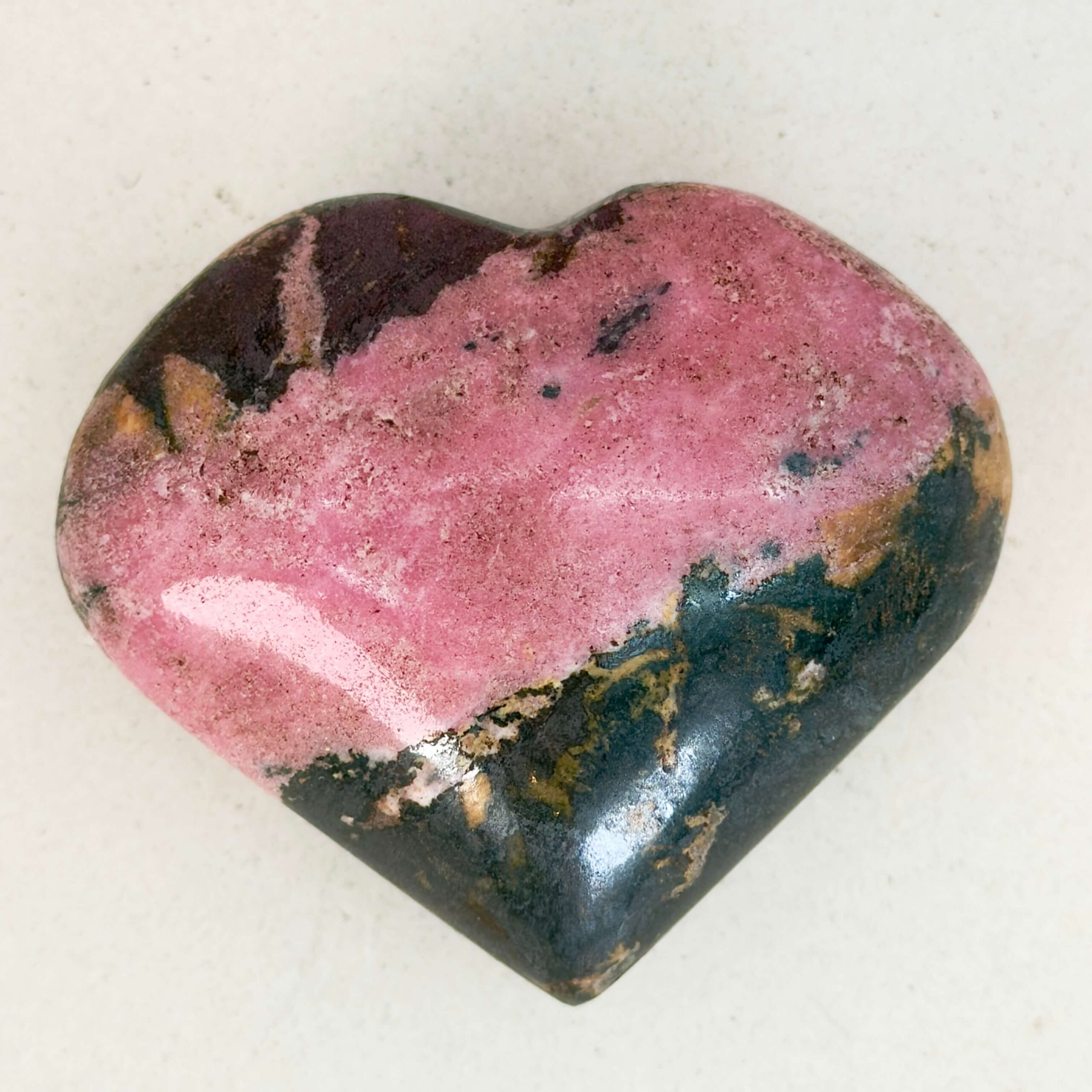 Rhodonit hjerte krystal sten i holder på hvid plade