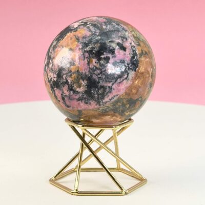 Rhodonit kugle krystal sten på stander på hvid plade med lyserød baggrund