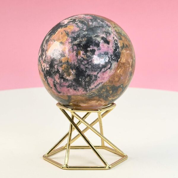 Rhodonit kugle krystal sten på stander på hvid plade med lyserød baggrund