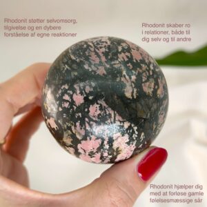 Rhodonit kugle krystal sten i hånd med hvid baggrund og med tags