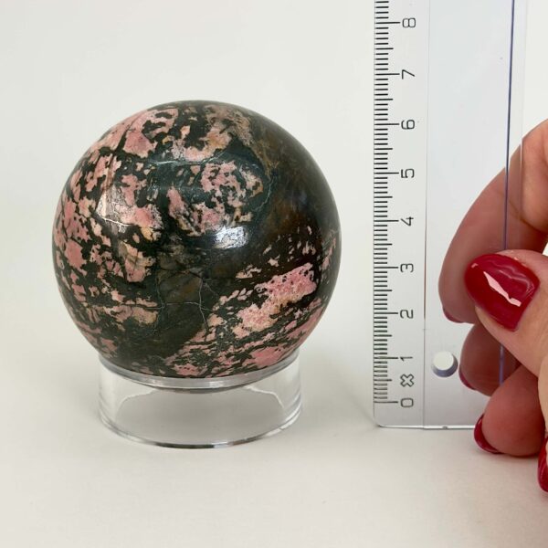 Rhodonit kugle krystal sten ved siden af lineal på hvid baggrund