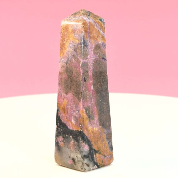 Rhodonit tårn krystal sten på hvid plade med lyserød baggrund