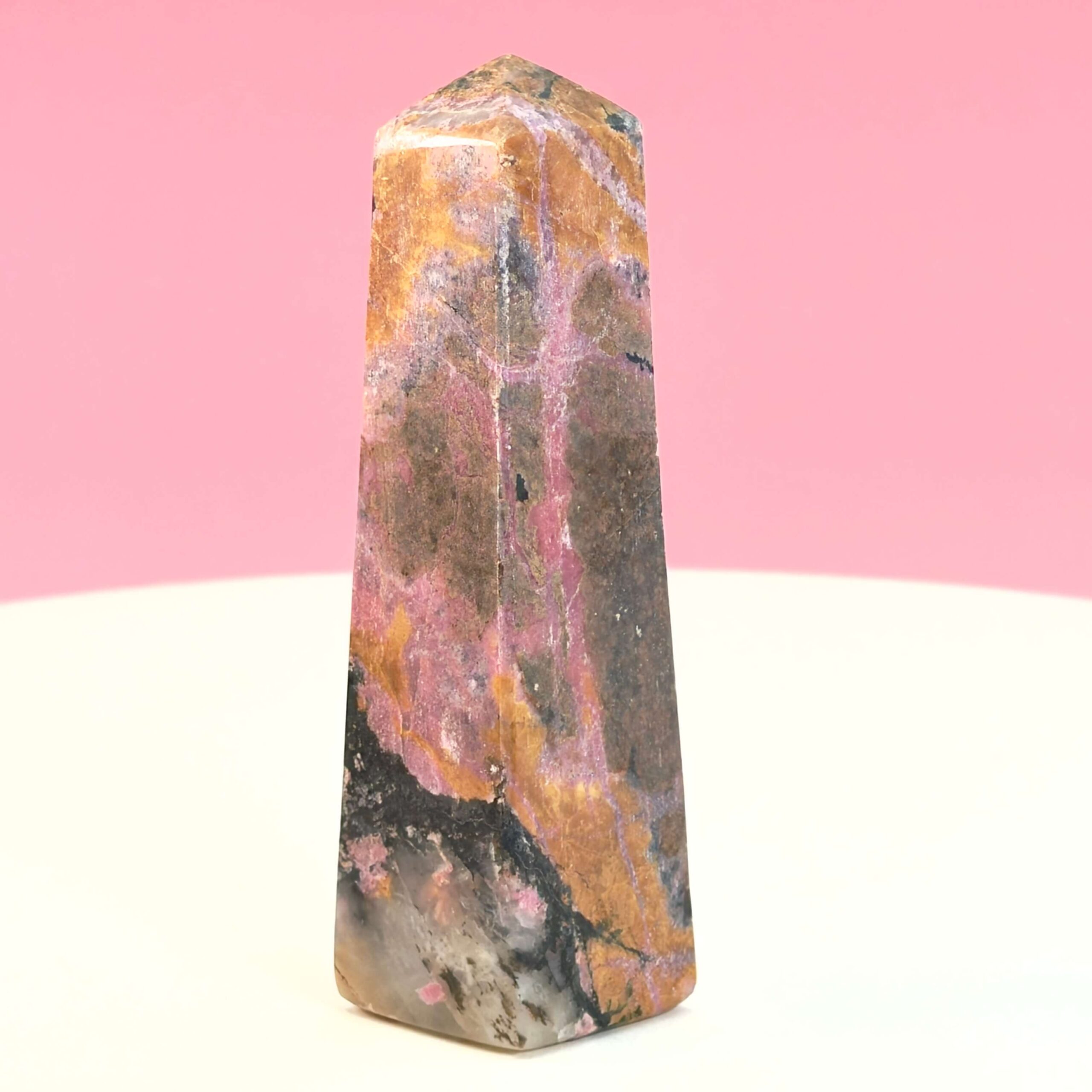 Rhodonit tårn krystal sten på hvid plade med lyserød baggrund