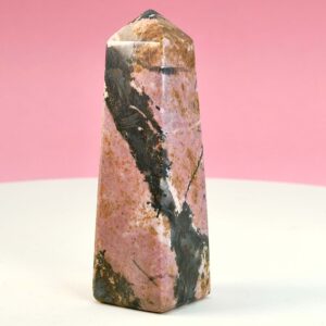 Rhodonit tårn krystal sten på hvid plade med lyserød baggrund