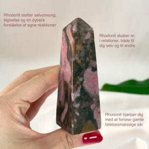 Rhodonit tårn krystal sten i hånd med hvid baggrund og med tags