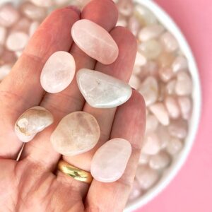 Rosakvarts Lommesten Krystal Sten samling i hånd på rosa baggrund