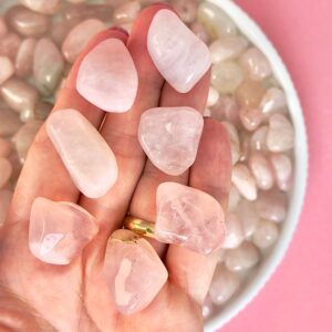 Rosakvarts Lommesten Krystal Sten samling i hånd på rosa baggrund