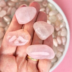 Rosakvarts Lommesten Krystal Sten samling i hånd på rosa baggrund