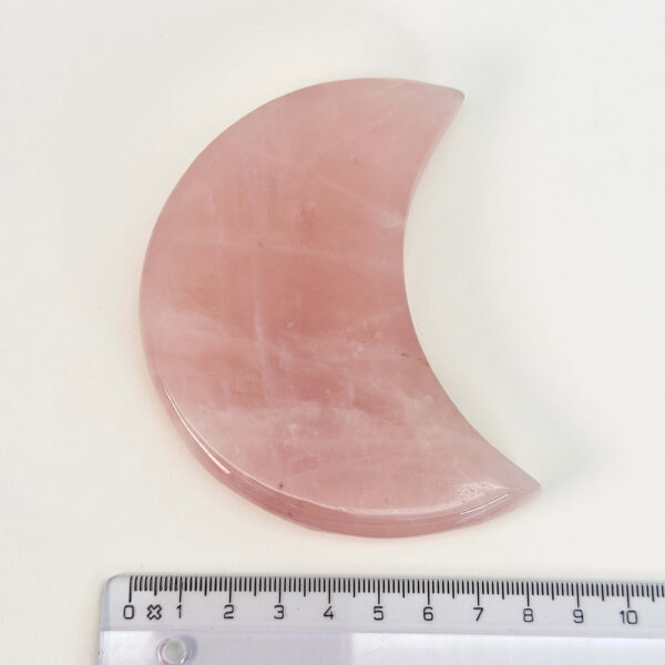 Rosakvarts Måne krystal sten med lineal på hvid baggrund