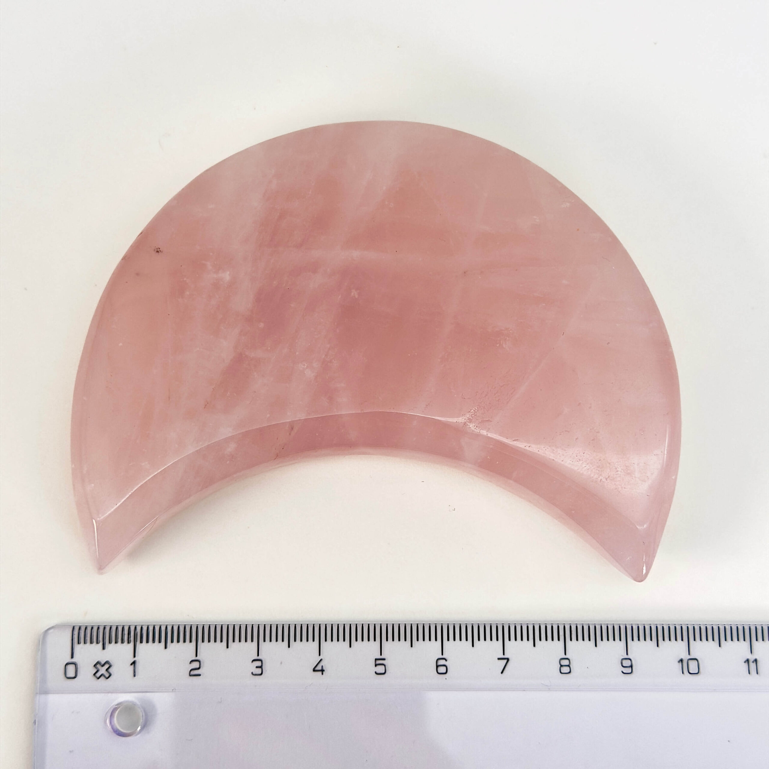 Rosakvarts Måne krystal sten med lineal på hvid baggrund