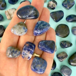 Sodalit Lommesten Krystal Sten samling i hånd på blå baggrund