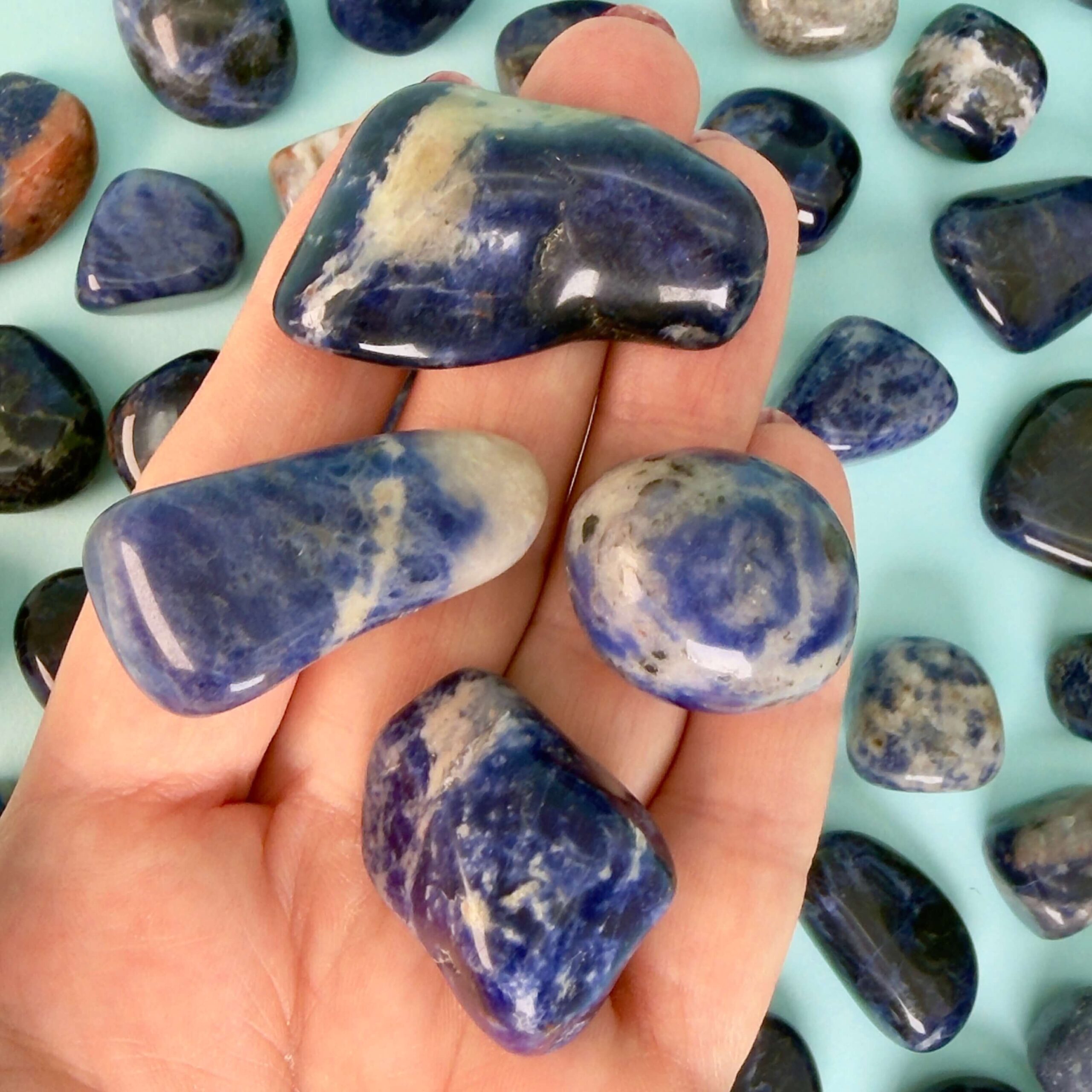 Sodalit Lommesten Krystal Sten samling i hånd på blå baggrund