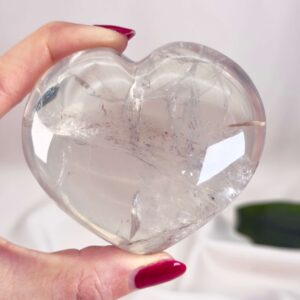 Bjergkrystal Hjerte krystal sten i hånd på hvid baggrundBjergkrystal Drage krystal sten i hånd på hvid baggrund
