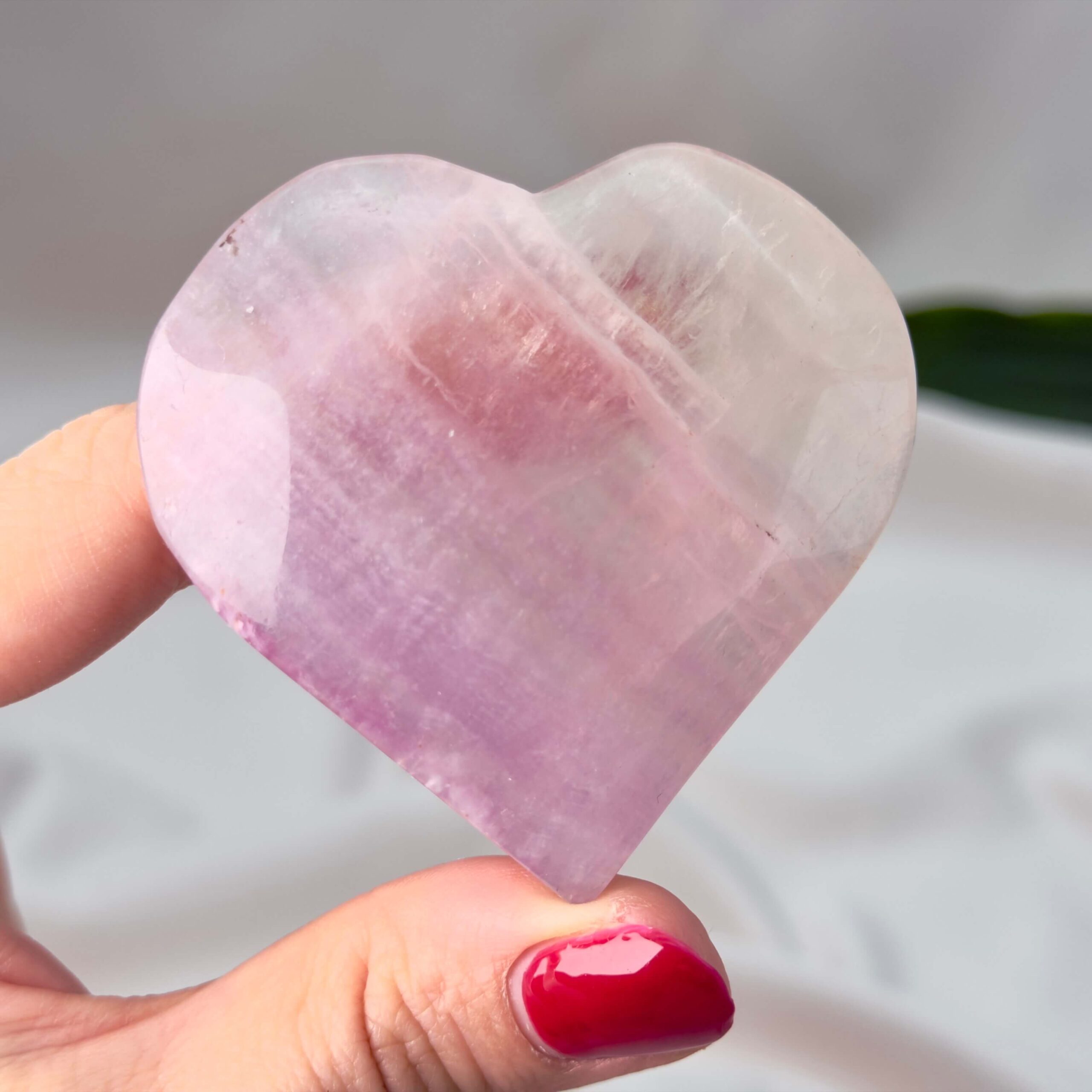 Fluorit Candy Hjerte Krystal Sten i hånd på hvid baggrund