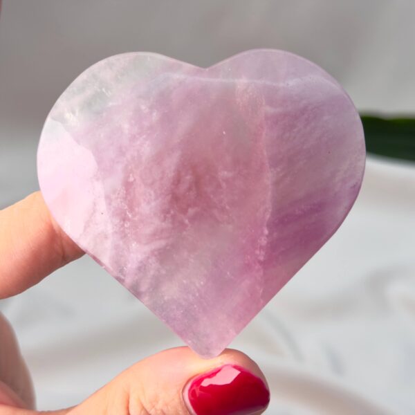 Fluorit Candy Hjerte Krystal Sten i hånd på hvid baggrund