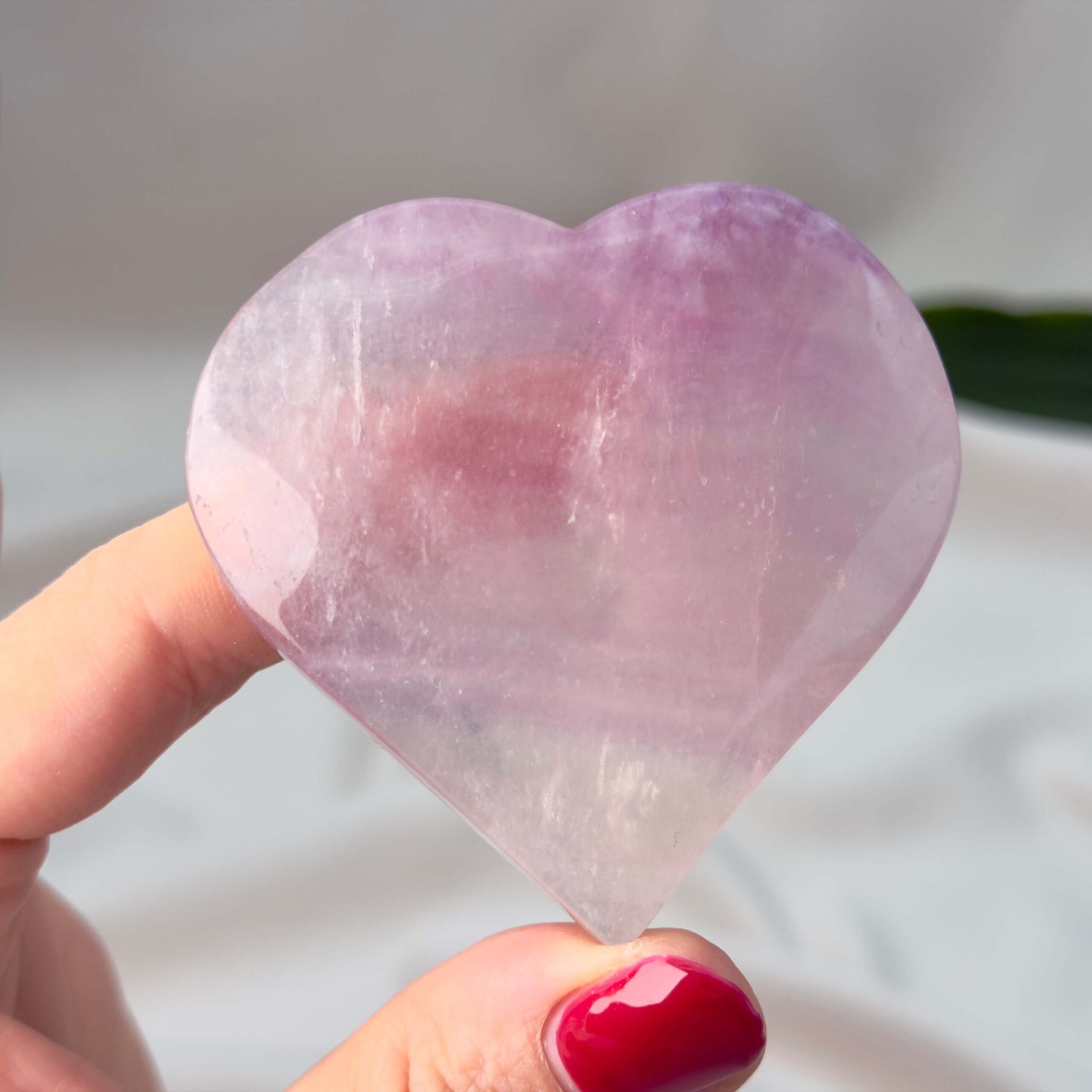 Fluorit Candy Hjerte Krystal Sten i hånd på hvid baggrund