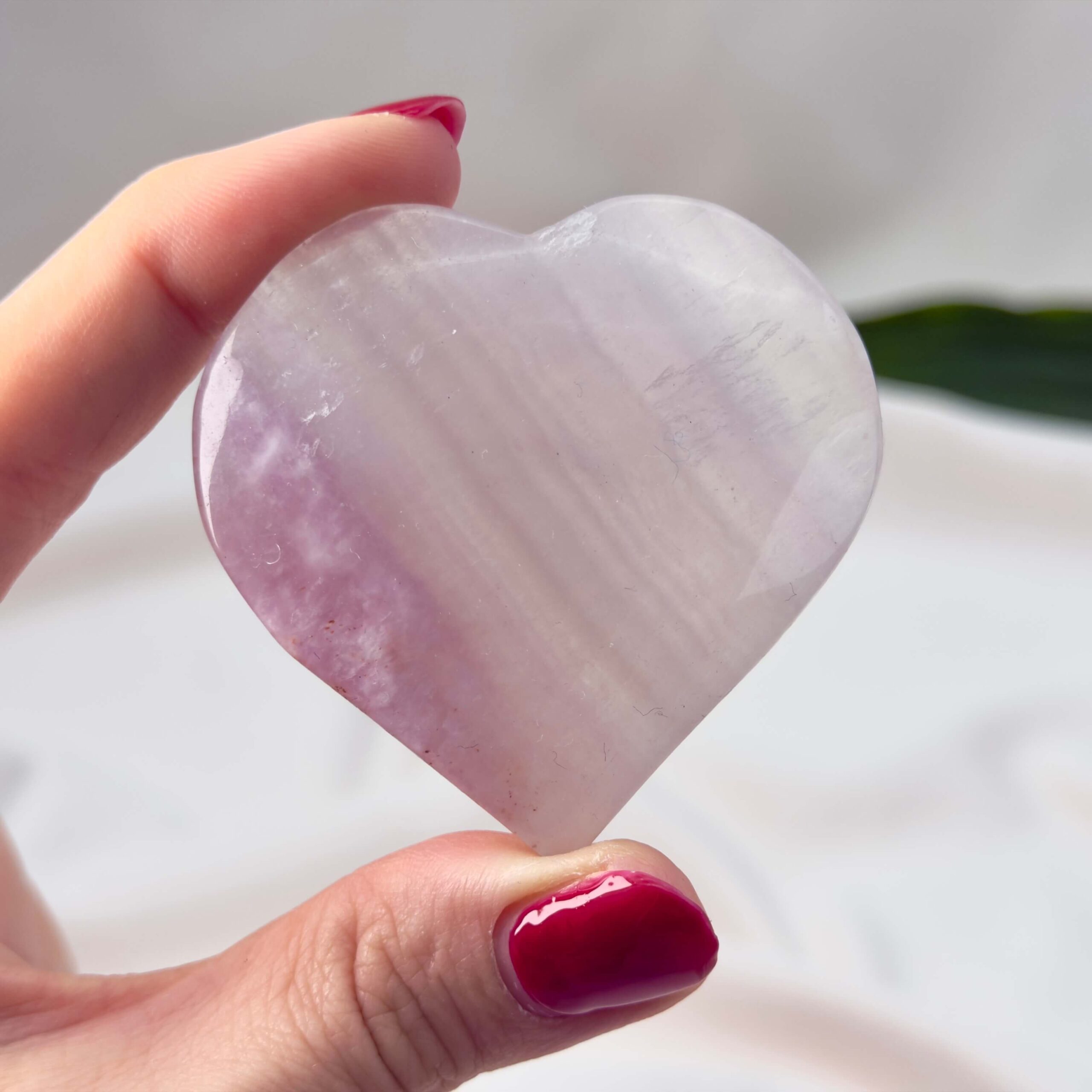 Fluorit Candy Hjerte Krystal Sten i hånd på hvid baggrund