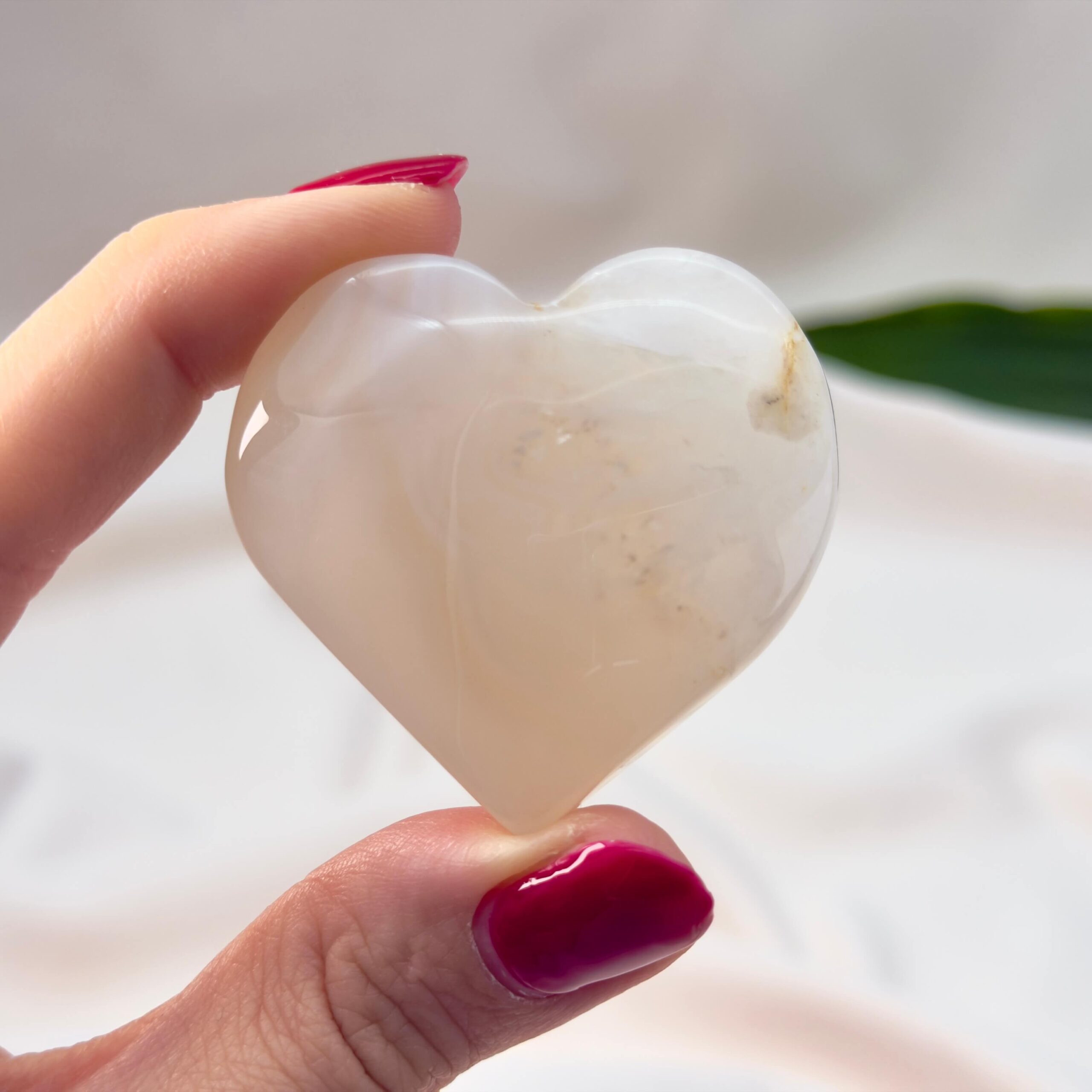 Fluorit Candy Hjerte Krystal Sten i hånd på hvid baggrund