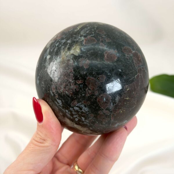 Granat Kugle krystal sten i hånd på hvid baggrund