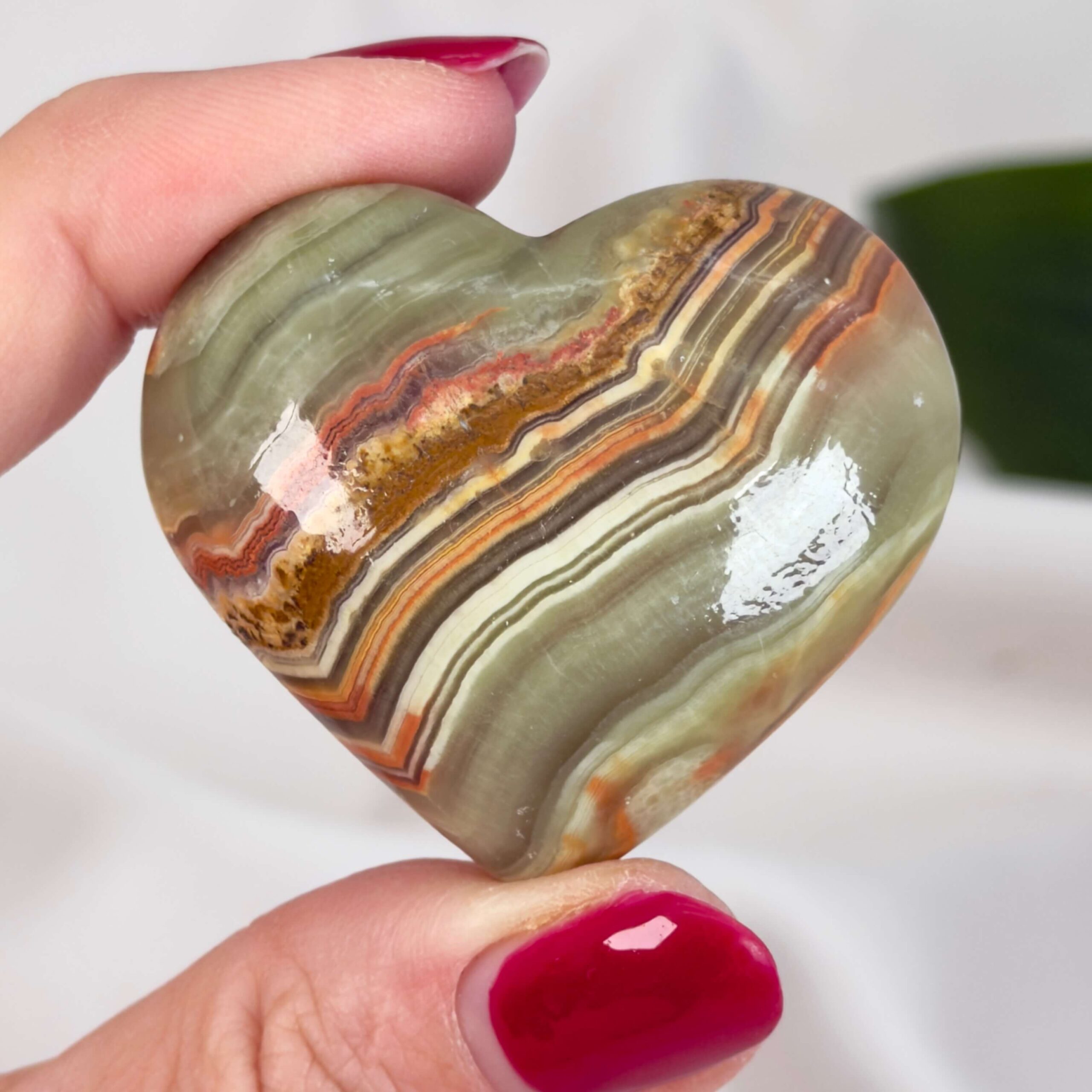 Grøn Onyx Hjerte krystal sten i hånd på hvid baggrund