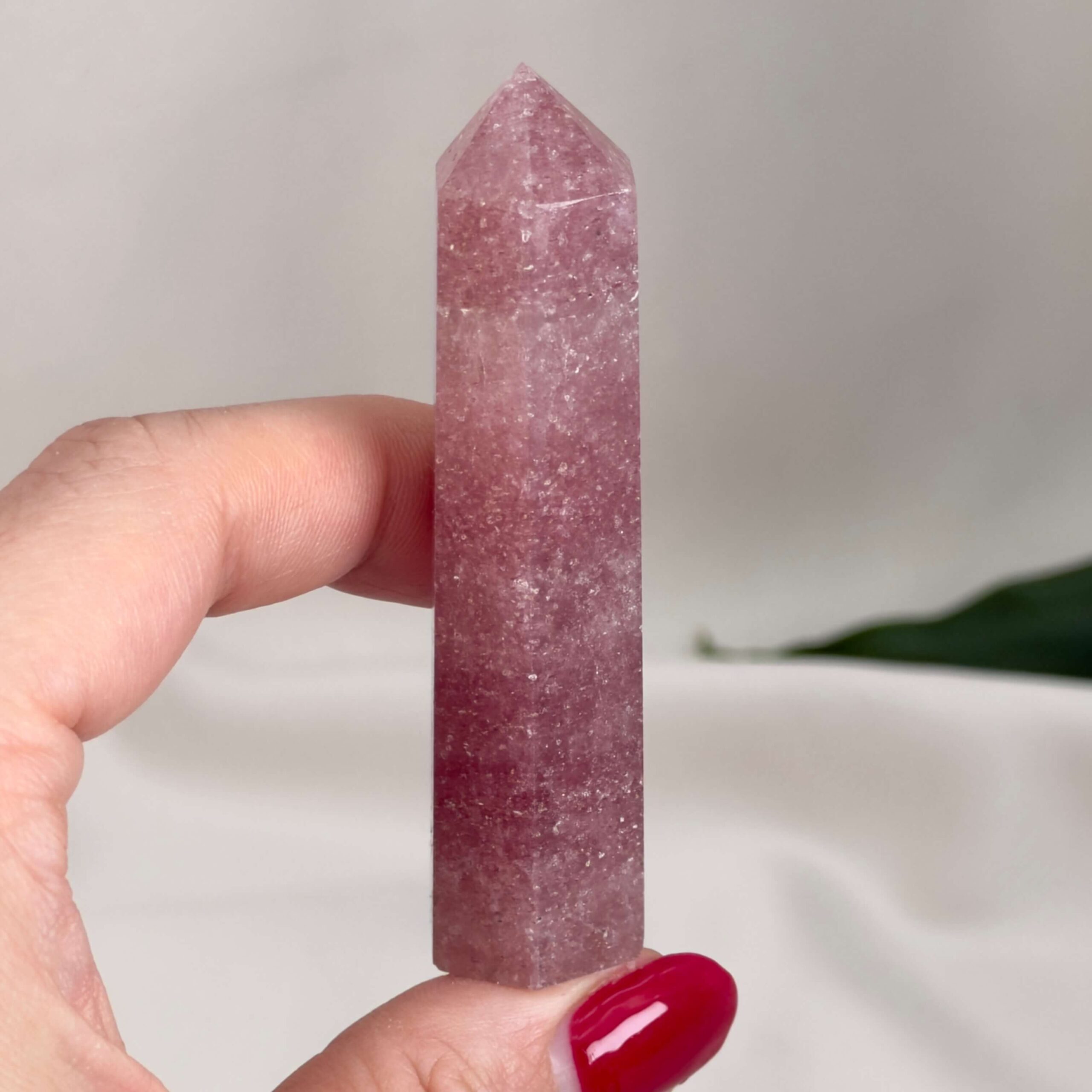 Jordbærkvarts tårn krystal sten i hånd på hvid baggrund