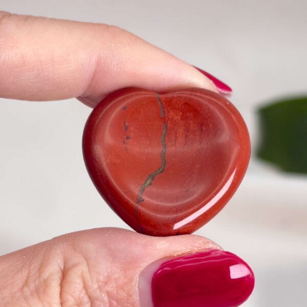 Rød Jaspis bekymringssten krystal sten i hånd på hvid baggrund